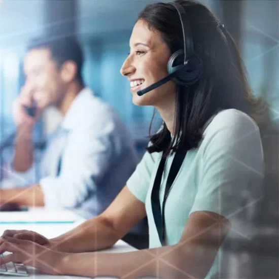 Woman smiling wearing a headset while working on a computer