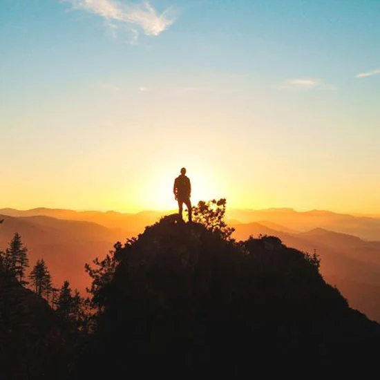 Person at the top of a mountain at sunrise