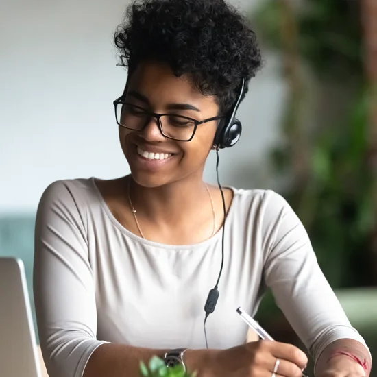 Young woman shown working on laptop with headset