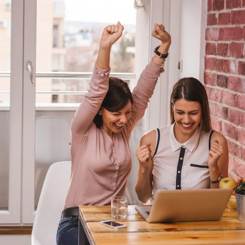 Women celebrating as the review information on their laptop