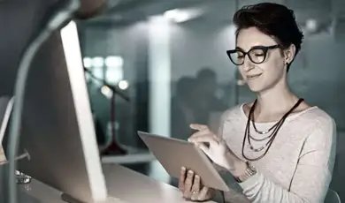 woman reviewing tablet in front of computer