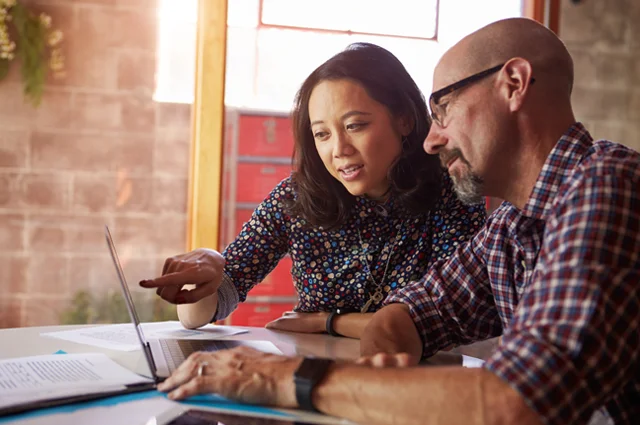 Man and woman colleagues working together reviewing information on laptop