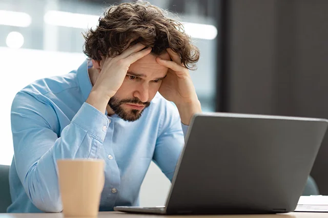 businessman looking at laptop overwhelmed and stressed out businessman looking at laptop overwhelmed and stressed out
