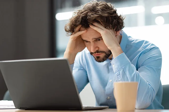 businessman looking at laptop overwhelmed and stressed out businessman looking at laptop overwhelmed and stressed out