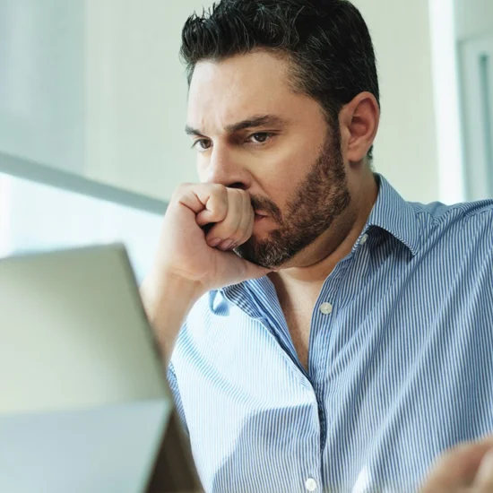 businessman reviewing information on laptop showing worried expression