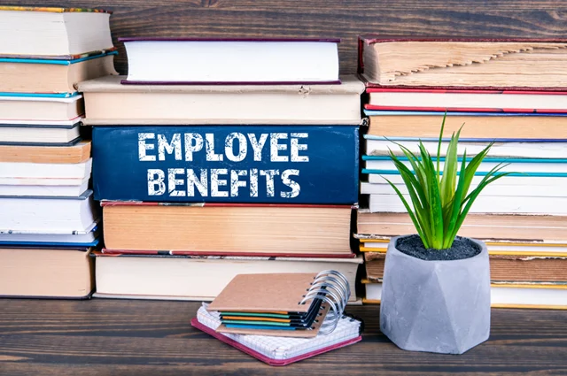 employee benefits book on table with other books stacked around it employee benefits book on table with other books stacked around it