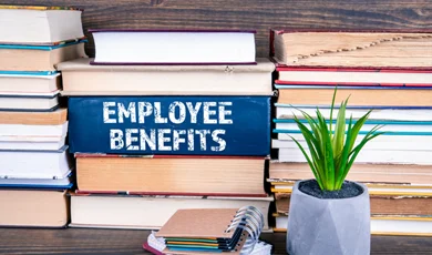 employee benefits book on table with other books stacked around it
