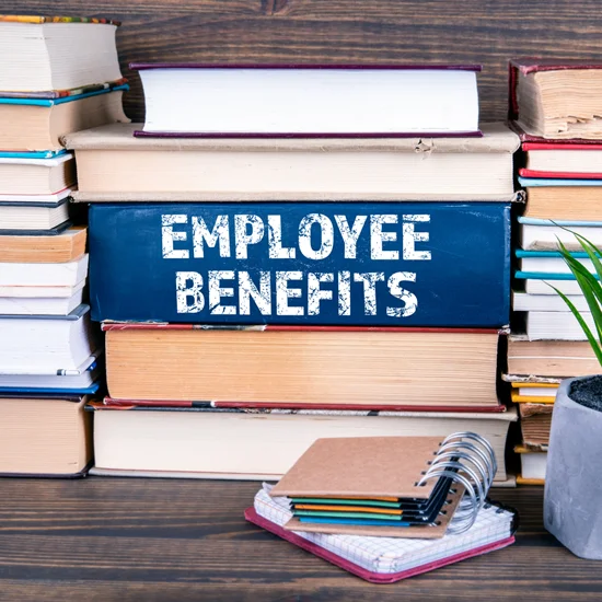 employee benefits book on table with other books stacked around it