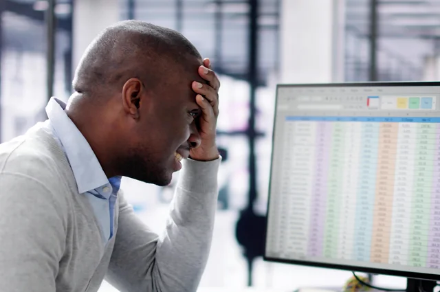 frustrated manager holds his head while viewing multiple computer screens and data frustrated manager holds his head while viewing multiple computer screens and data