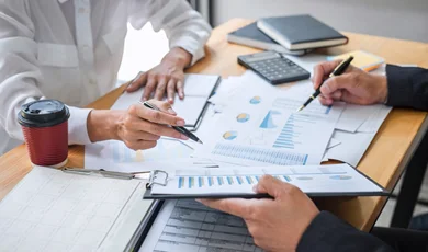 business colleagues analyze charts graphs and documents pens and calculator