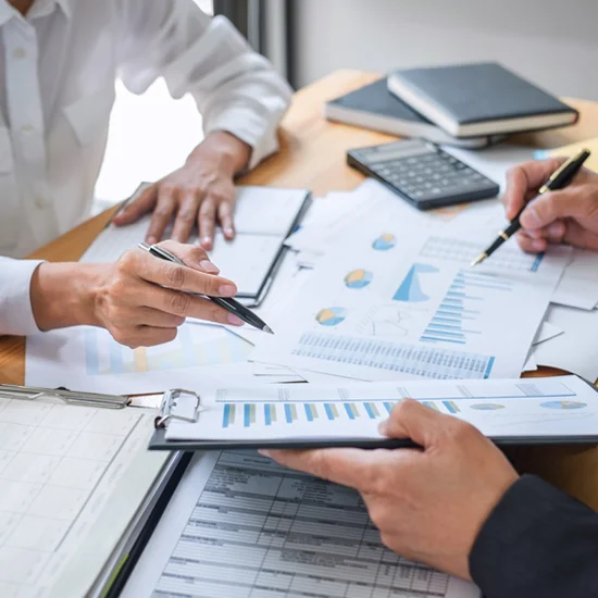 business colleagues analyze charts graphs and documents pens and calculator