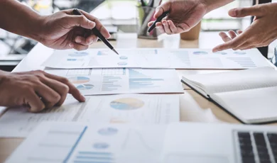 business colleagues discussing reports and analytics spread across desk