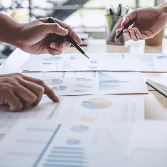 business colleagues discussing reports and analytics spread across desk