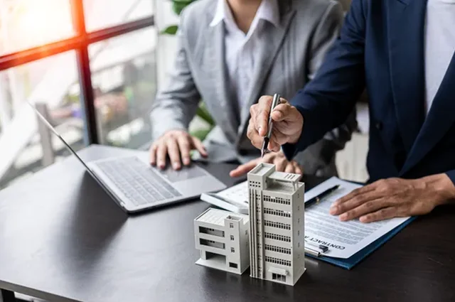 colleagues reviewing model of commercial building discussing p&c insurance