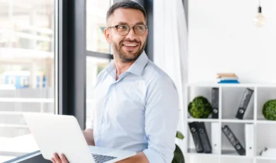 male businessman holding laptop in front of window
