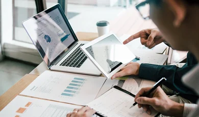 businessmen reviewing operational data and analytics on tablets and a laptop