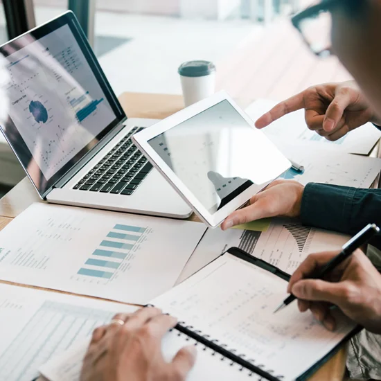 businessmen reviewing operational data and analytics on tablets and a laptop