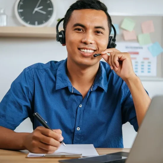 man with headphones working in office with papers and laptop on desk