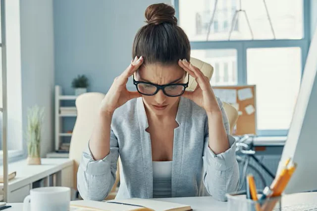 inefficient stressed young woman keeping her head in hands while sitting