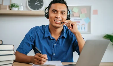 man with headphones working in office with papers and laptop on desk