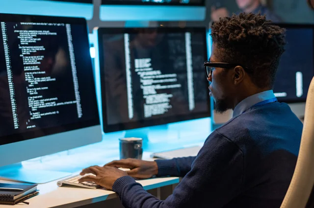 it-engineer decoding data while sitting in front of computer monitors