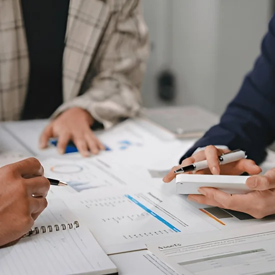 colleagues gathered around a table, reviewing documents and charts actively engaged in discussion and analysis
