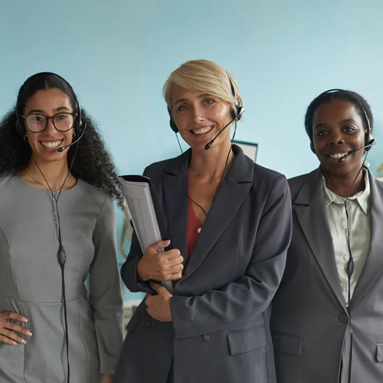 three women are smiling and wearing headsets and business attire