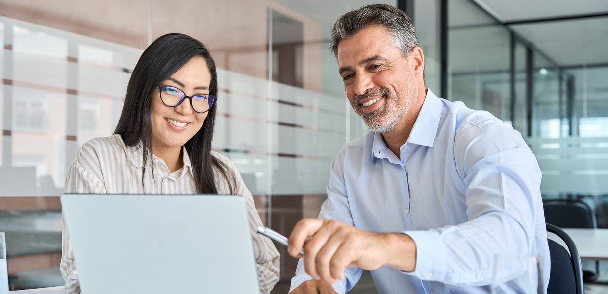 Two colleagues reviewing information together on a laptop in an office